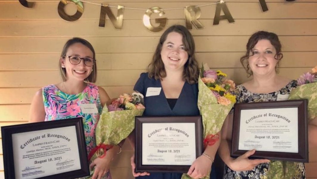 three women holding diplomas